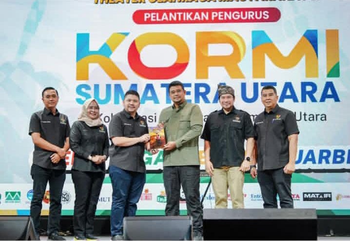 penulis buku dan Bobby Nasution menunjukkan buku yang diterbitkan CV Firaz Media